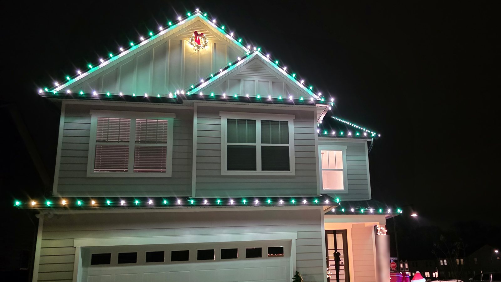 Two-story home with green and white roofline holiday lights and a lit walkway border — a 2025 Viking Pro Solutions install