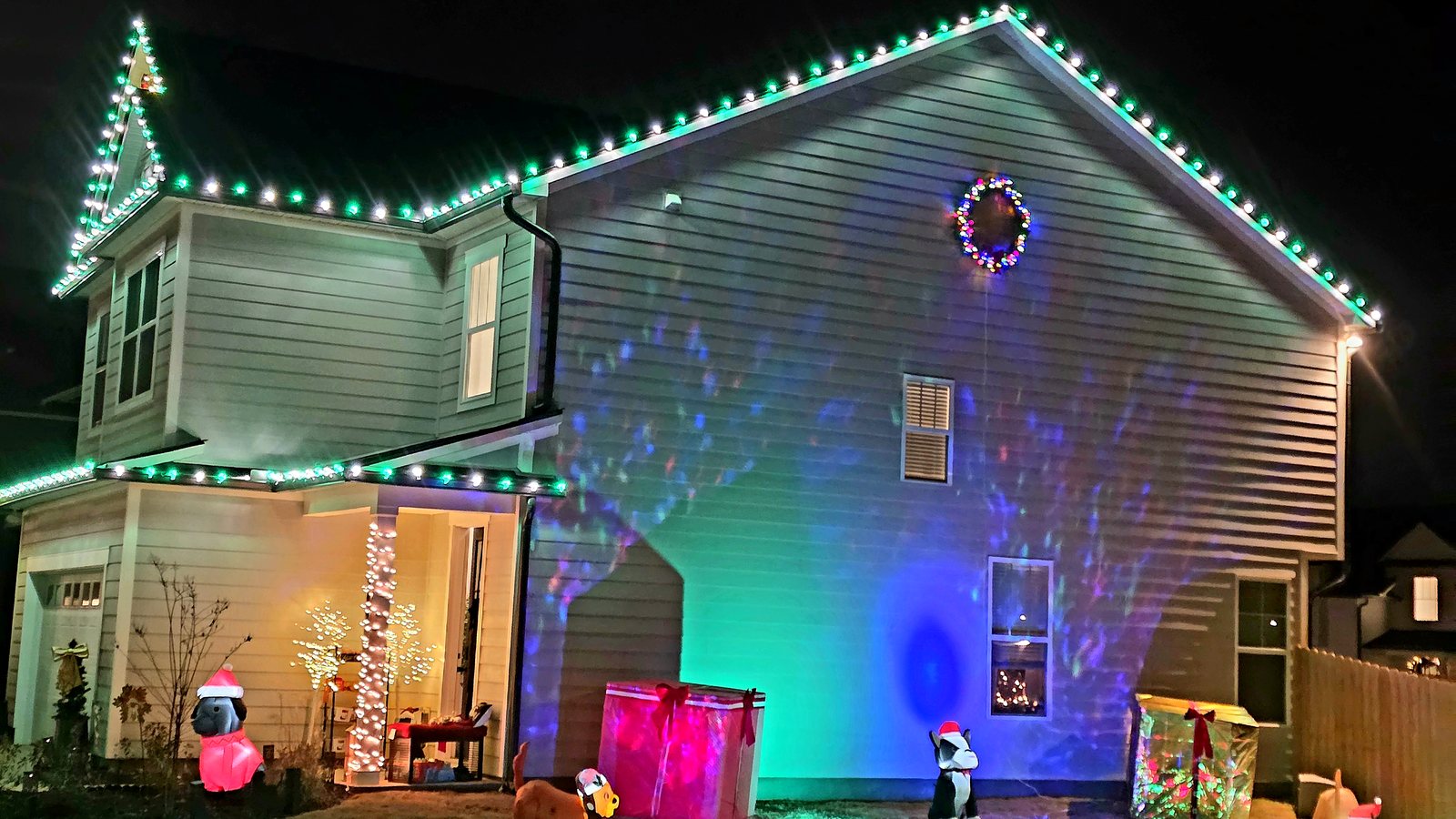 Two-story home with green and white C9 roofline lights and a lit lawn border — a 2025 Viking Pro Solutions install